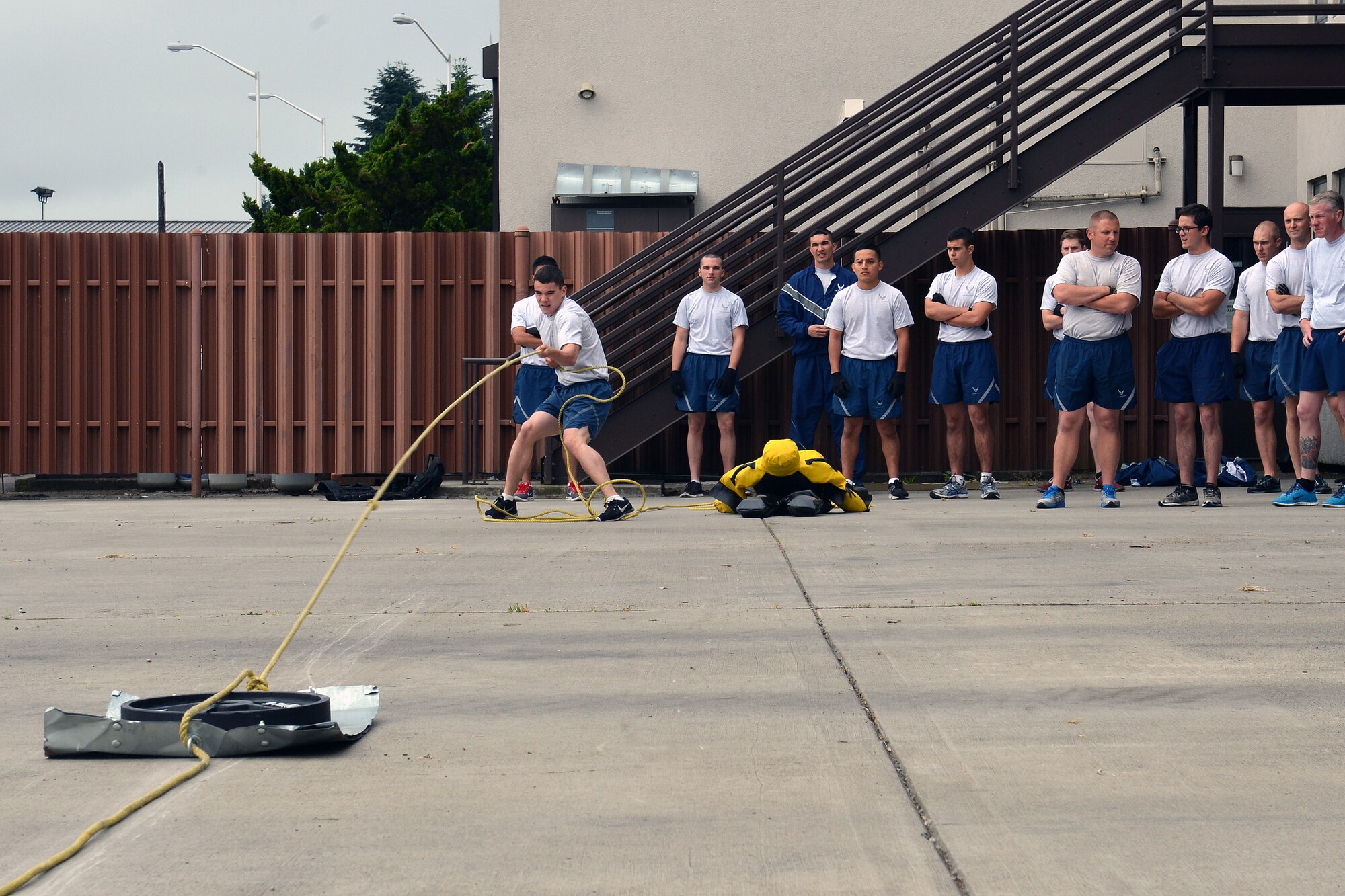 Airmen 1st Class Jeremiah Alejandro, 627th Civil Engineer Squadron explosive ordnance disposal specialist, pulls a sled during the third part of the CE fitness challenge at the fire station June 11, 2014, at Joint Base Lewis-McChord, Wash. After the dummy drag, Airmen pulled a weighted metal sled across the ground while their teammate runs to the next part of the challenge. (U.S. Air Force photo/Senior Airmen Brenden Marlin)