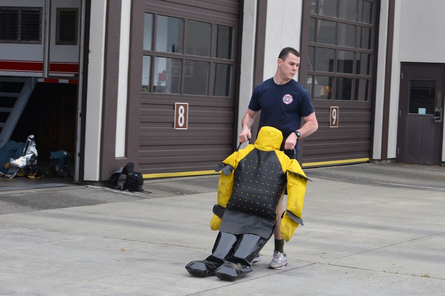 Airmen 1st Class Christian Prosser, 627th Civil Engineer Squadron fire fighter, pulls on the dummy during the second part of the CE fitness challenge at the fire station June 11, 2014, at Joint Base Lewis-McChord, Wash. After his teammate flipped the tire to him, Prosser dragged a weighted human dummy back across as his partner hurried to the next part of the challenge. (U.S. Air Force photo/Senior Airmen Brenden Marlin)