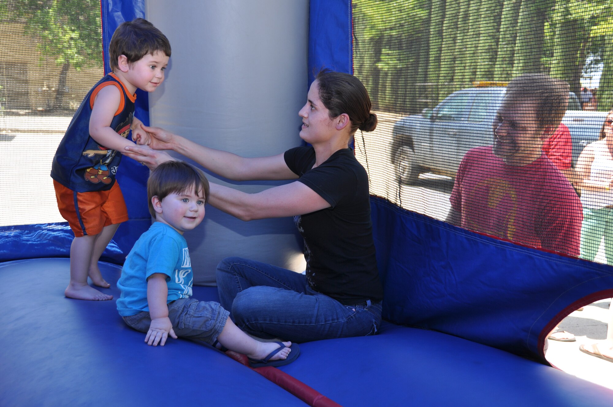 Wing picnic goer plays with her two sons while her husband looks on outside the bounce house at the 940th Wing Family Day picinic, June 8, 2014. Airmen, along with friends, family, employers and the wing’s honorary commanders gathered for an afternoon of food and friendly competition. (U.S. Air Force photo by Tech. Sgt. Heather Skinkle/Released)