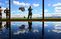 DAVIS-MONTHAN AIR FORCE BASE, Ariz. – Water from a recent rainfall reflects a pararecueman (PJ) assigned to the 306th Rescue Squadron completing his jump during a training mission March 2 in Eloy, Arizona.  PJ’s are specifically organized, trained and equipped to conduct personnel recovery operations in hostile or denied areas as a primary mission. The 306th RQS is a subordinate unit of the 943rd Rescue Group, which trains and equips Citizen Airmen to perform personnel recovery operations worldwide. (U.S. Air Force photo/Tech. Sgt. Frank Oliver)