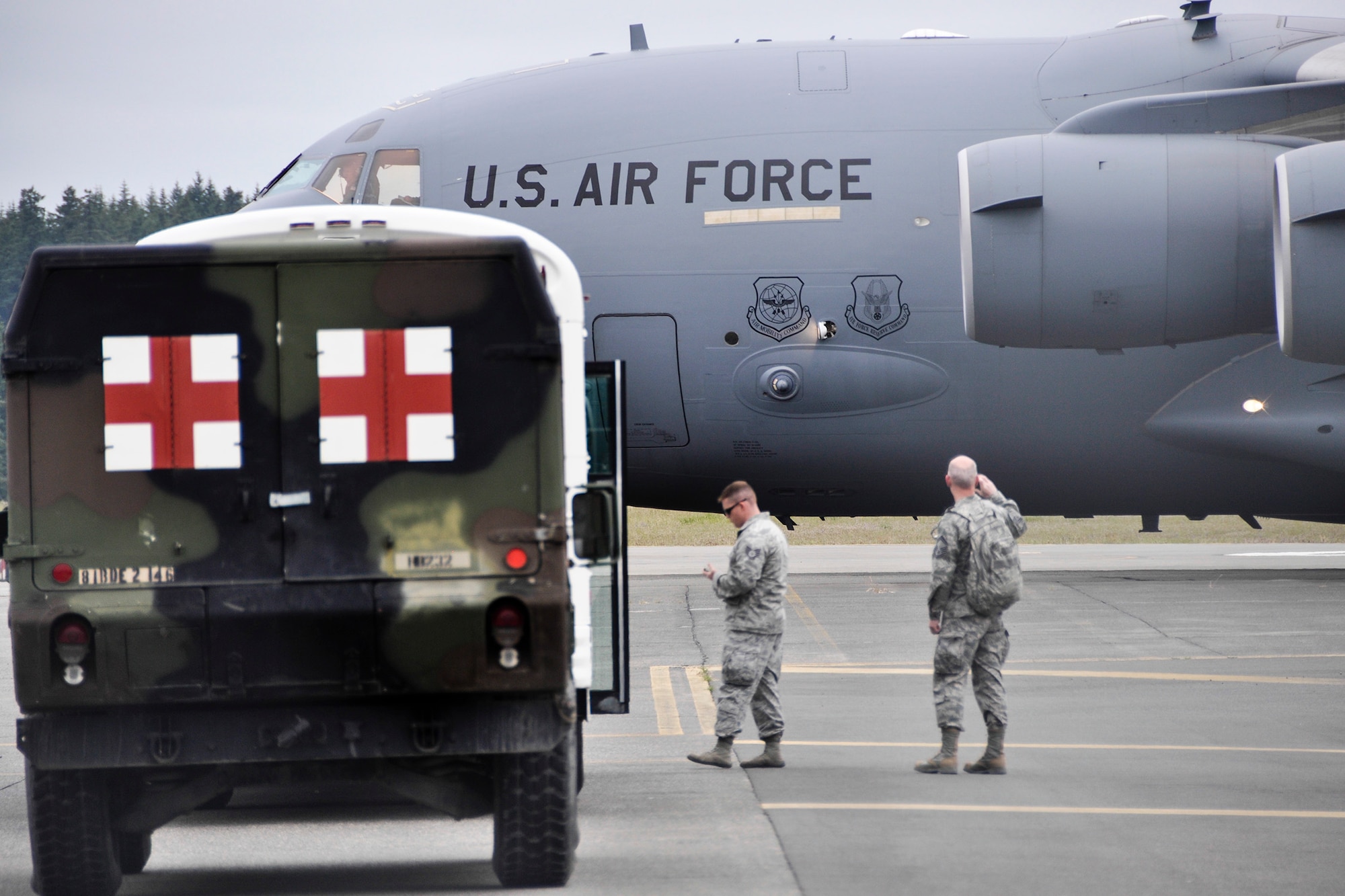 Reservists from the 446th Aeromedical Staging Squadron wait for a 446th Airlift Wing, C-17 Globemaster III to taxi in order to load it with patients for during the Rainer Medic course June 3 at Joint Base Lewis-McChord, Washington. (U.S. Air Force Reserve photo by Jake Chappelle)