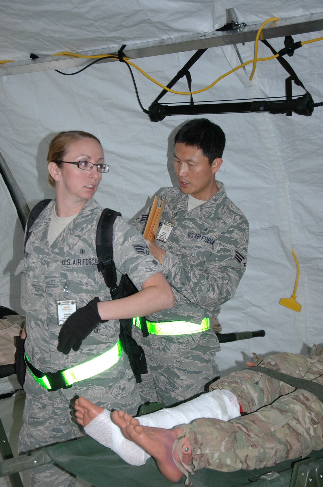 Senior Airman Steve Kwak places patient information in a backpack carried by Senior Airman Brittney Taylor in anticipation of a bug out order during the Rainier Medic course June 3 at Joint Base Lewis-McChord, Washington.  Both Kwak and Taylor are assigned to the 446th Aeromedical Staging Squadron at McChord Field. (U.S. Air Force Reserve photo by Sandra Pishner)