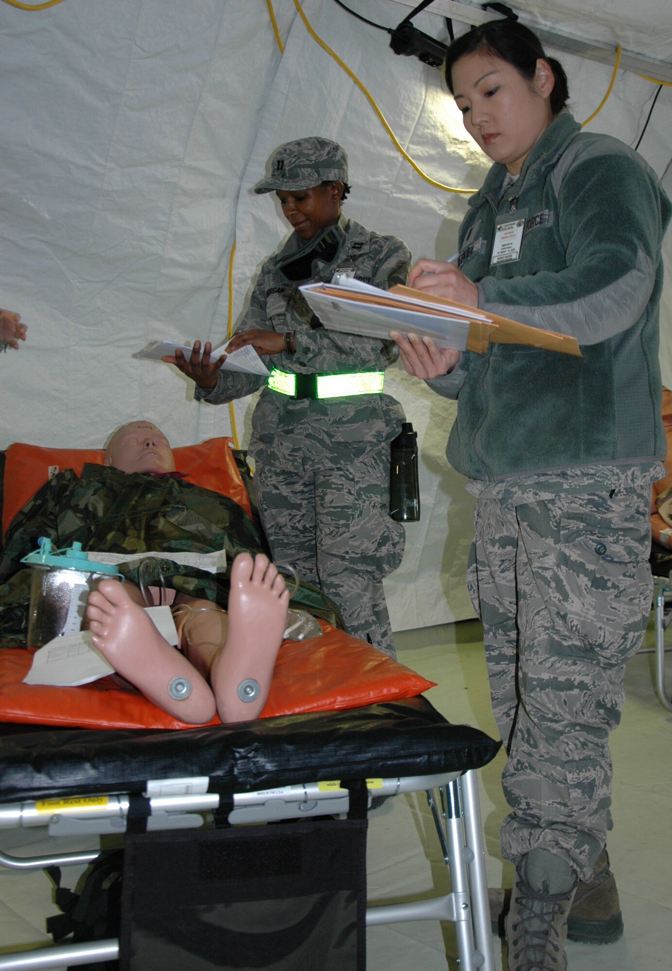 Capt. Lorraine Morgan, (left) and 1st Lt. Jennifer Weekley, both with the 446th Aeromedical Staging Squadron, check a on a patient in their care at the En Route Patient Staging facility (U.S. Air Force Reserve photo by Sandra Pishner)
