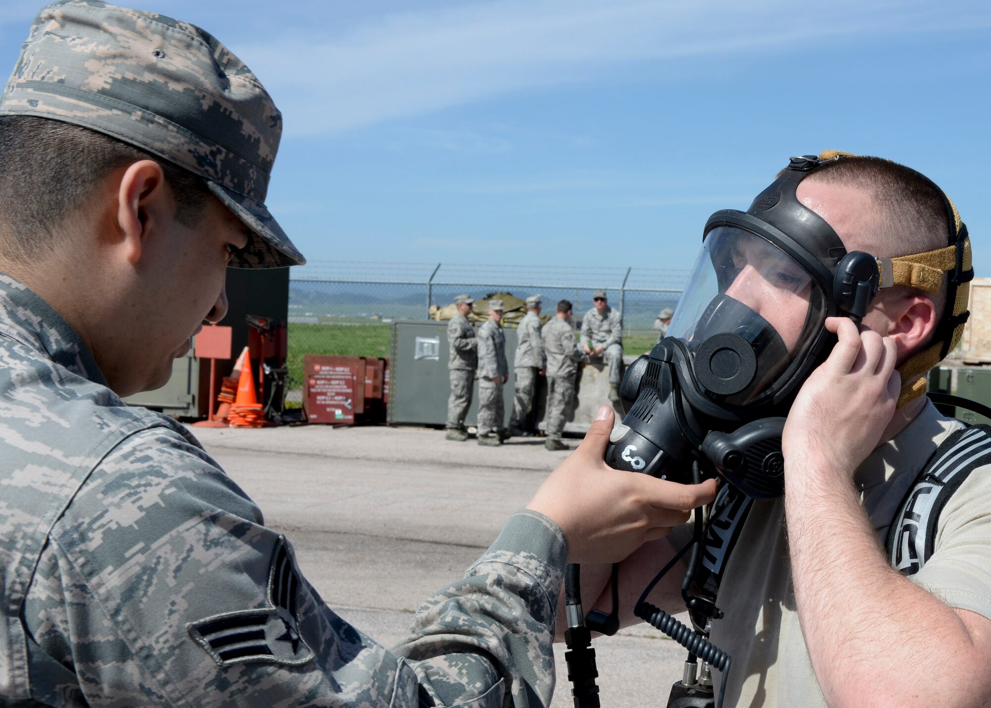 Senior Airman  Roger Pedraza, 28th Medical Operations Squadron bioenvironmental technician, assists Airman 1st Class Ronald Reynolds, 28th Civil Engineer Squadron emergency management technician, with his respiratory mask during an Integrated Base Emergency Response Capabilities Training at Ellsworth Air Force Base, S.D., May 22, 2014. The mask and Level-A suit protect emergency responders from hazardous materials and contaminated environments. (U.S. Air Force photo by Senior Airman Anania Tekurio/Released)