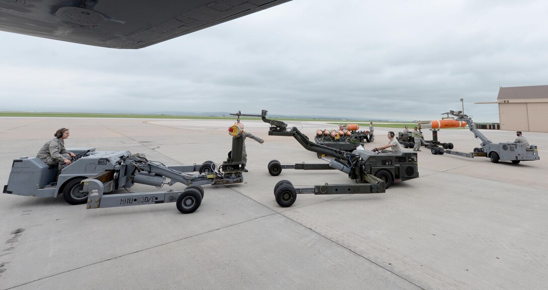 Load crew members from the 28th Munitions Squadron transfer Mk- 62 and 65 Quick Strike mine munitions to load into a B-1 bomber during a joint mission exercise at Ellsworth Air Force Base, S.D., June 3, 2014. Ellsworth Airmen teamed up with Sailors from the Naval munitions command, Seal Beach, Calif., to build, load and employ Mk-62 and 65 mines as a part of the exercise that provided a variety of learning opportunities between the two service branches. (U.S. Air Force photo by Airman 1st Class Rebecca Imwalle/Released)