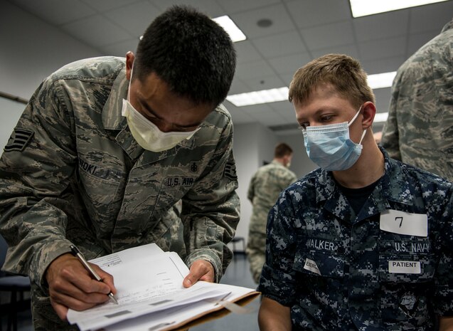 Seaman Recruit Marcus Walker, a role player from Naval Nuclear Power Training Unit, is evaluated by a member of the 628th Medical Group during the Disease Containment Exercise June 4, 2014, at Joint Base Charleston, S.C. Personnel from the 437th Airlift Wing and the 628th Air Base Wing, along with Naval Nuclear Power Training Command Sailors and approximately 85 volunteers participated in the exercise. (U. S. Air Force photo/ Senior Airman Dennis Sloan)