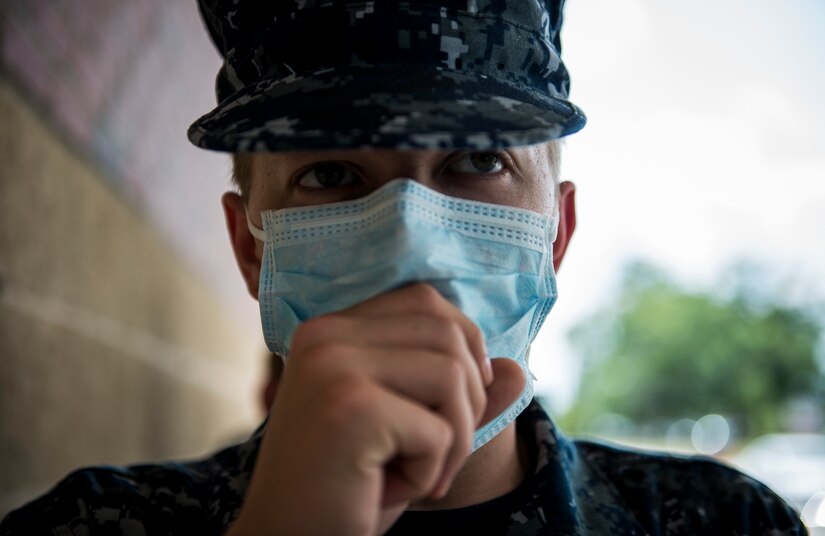 Seaman Recruit Marcus Walker, role player from Naval Nuclear Power Training Unit, coughs while waiting to be evaluated by a member of the 628th Medical Group during the Disease Containment Exercise June 4, 2014, at Joint Base Charleston, S.C. Personnel from the 437th Airlift Wing and the 628th Air Base Wing, along with Naval Nuclear Power Training Command Sailors and approximately 85 volunteers participated in the exercise. (U. S. Air Force photo/ Senior Airman Dennis Sloan)