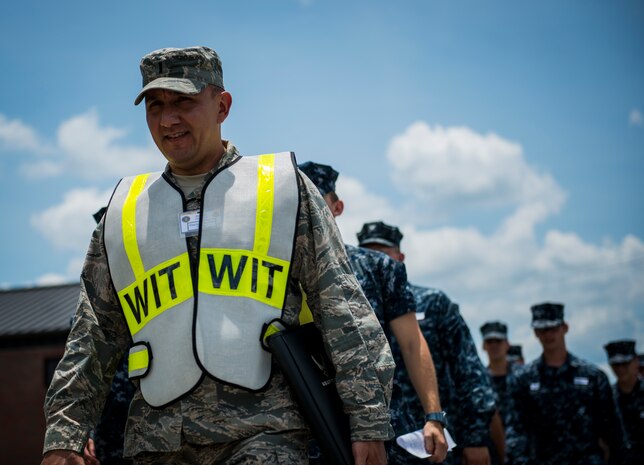 An exercise evaluation team member leads a group of 25 Sailors to be evaluated by 628th Medical Group personnel during the Disease Containment Exercise June 4, 2014, at Joint Base Charleston, S.C. Personnel from the 437th Airlift Wing and the 628th Air Base Wing, along with Naval Nuclear Power Training Command Sailors and approximately 85 volunteers participated in the exercise. (U. S. Air Force photo/ Senior Airman Dennis Sloan)