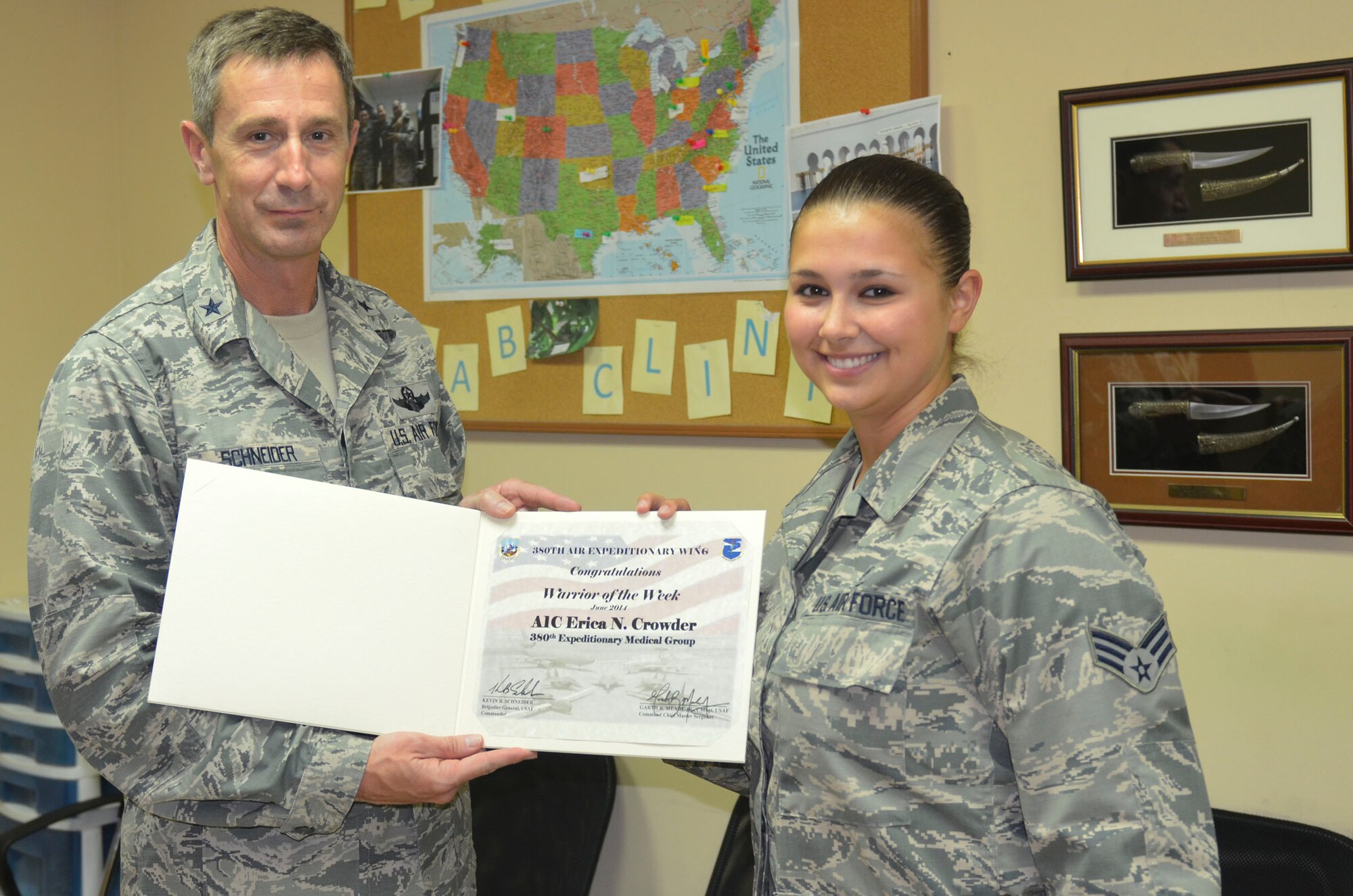Brig. Gen. Kevin Schneider, 380th Air Expeditionary Wing commander, presents Senior Airman Erica Crowder, 380th Expeditionary Medical Group, a warrior of the week certificate at an undisclosed location in Southwest Asia, June 12, 2014. Crowder, a native of Blountville, Tenn., is deployed from Joint Base Langley Eustis, Va. (U.S. Air Force photo by Maj. Jefferson S. Heiland)