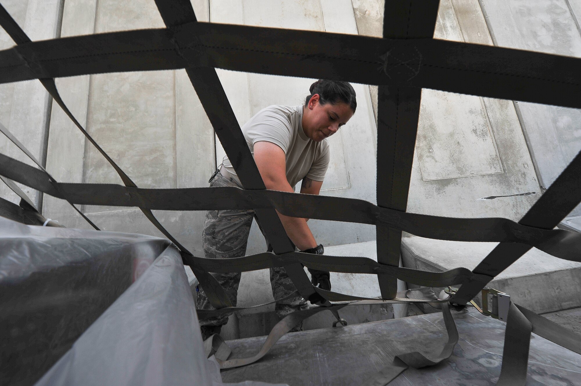 Senior Airman Heather Rossi, 380th Expeditionary Logistics Readiness Squadron, removes netting from a cargo pallet position June 11, 2014, at an undisclosed location in Southwest Asia.  The pallet was part of a shipment carrying supplies for the base.  (U.S. Air Force photo by Tech. Sgt. Russ Scalf/Released)