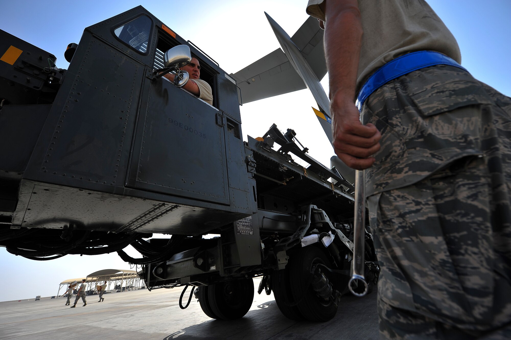 Staff Sgt. Everett Johnson III inspects a Tunner 60K cargo loader driven by Tech. Sgt. Thomas Brown, both from the 380th Expeditionary Logistics Readiness Squadron, June 11, 2014, at an undisclosed location in Southwest Asia. Down-loading cargo is one of many tasks accomplished by Air Terminal Operations Center Airmen.  (U.S. Air Force photo by Tech. Sgt. Russ Scalf/Released)