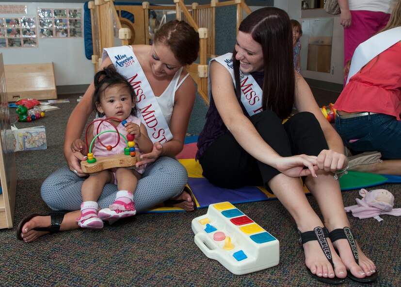 Alyssa Mills, Miss Midstate, left, and Jenna Hitchens, Miss Peach Blossom, interact with a  toddler during a Miss Delaware contestant tour June 10, 2014, at the Child Development Center on Dover Air Force Base, Del. The contestants visited with dozens of children at the center. (U.S. Air Force photo/Airman 1st Class Zachary Cacicia)