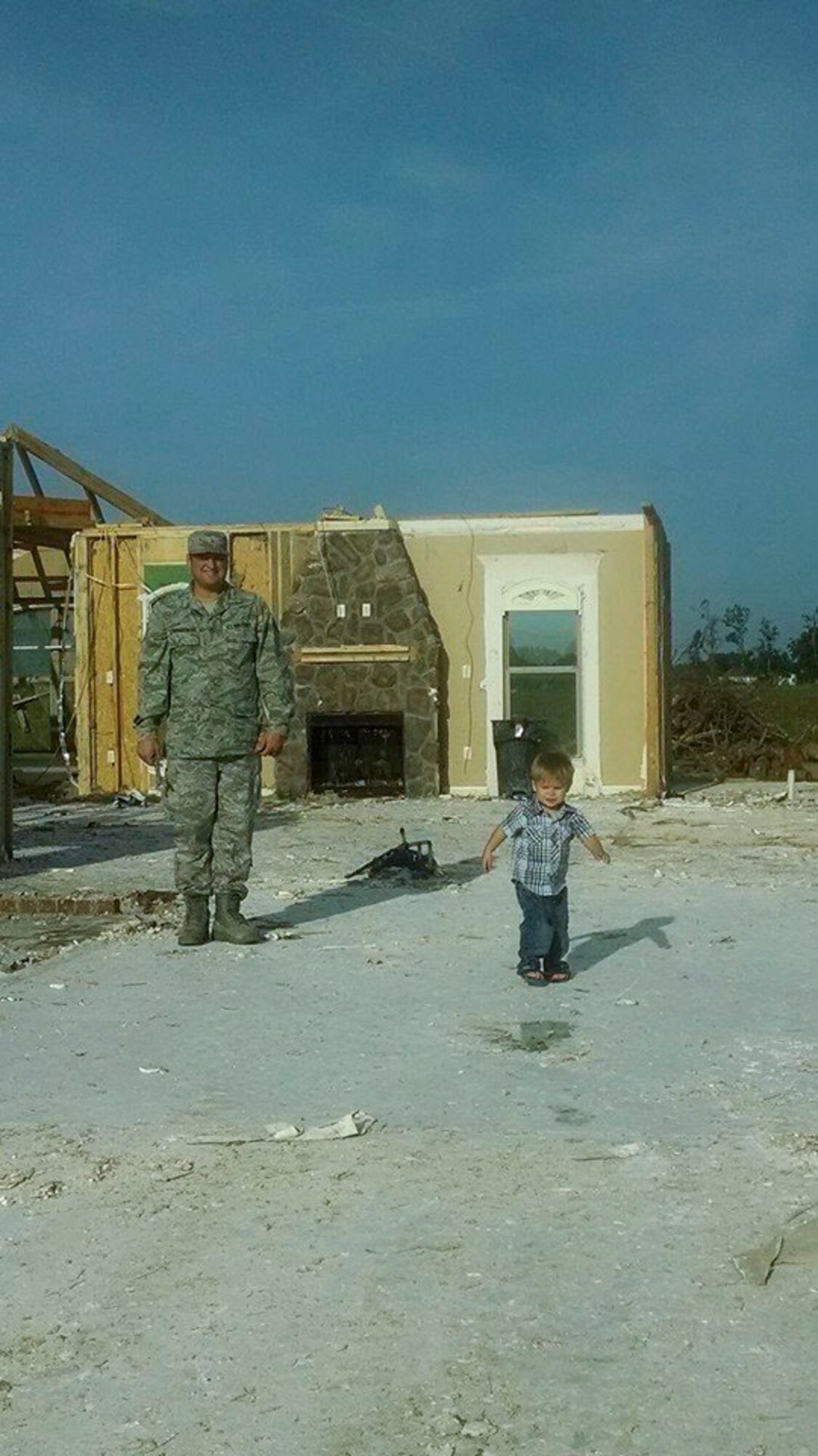 Staff Sgt. Mark Lewandowski, a 19th Maintenance Squadron aircraft fuels systems craftsman, watches his two-year-old son, Kayden, play on the foundation where their home once stood in Vilonia Ark. The Lewandowski family is currently rebuilding their new home in the same location. (courtesy photo)           