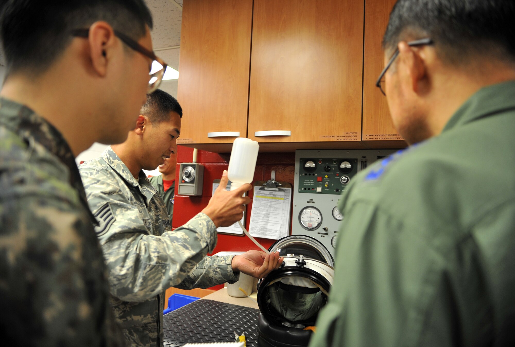 Staff Sgt. Jimmy Sayarath, 9th Physiological Support Squadron launch and recovery technician, Beale Air Force Base, Calif., demonstrates how U-2 Dragon Lady pilots drink water during flight to Republic of Korea air force Lt. Gen. Jae-Bock Park, ROK Air Force Operations Command commander, during an immersion tour at Osan Air Base, ROK, June 11, 2014. U-2 pilots are given a physical before each flight, including a blood pressure and temperature reading. (U.S. Air Force photo/Airman 1st Class Ashley J .Thum)