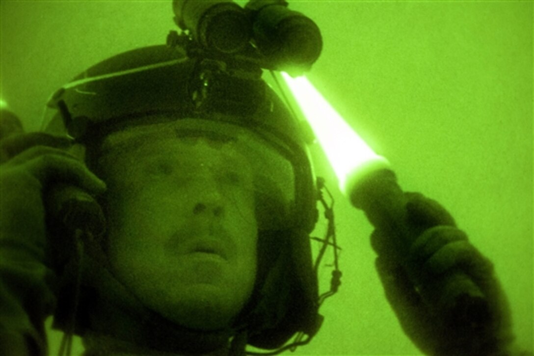 As through a night-vision device, Army Sgt. 1st Class Louis Lawton guides a Black Hawk helicopter during slingload training on Camp Johnson in Colchester, Vt., June 5, 2014. Lawton is assigned to Company C, 3rd Battalion, 126th Aviation Regiment. 