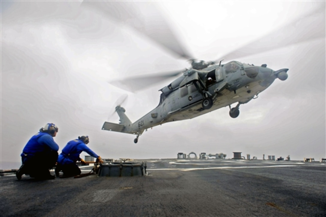 U.S. Navy sailors prepare to chain down an incoming helicopter on the the guided-missile destroyer USS John S. McCain in the Philippine Sea, June 9, 2014. The McCain is on patrol with the George Washington Carrier Strike Group supporting security and stability in the Indo-Asia-Pacific region. The helicopter is assigned to Helicopter Sea Combat Squadron 12. 