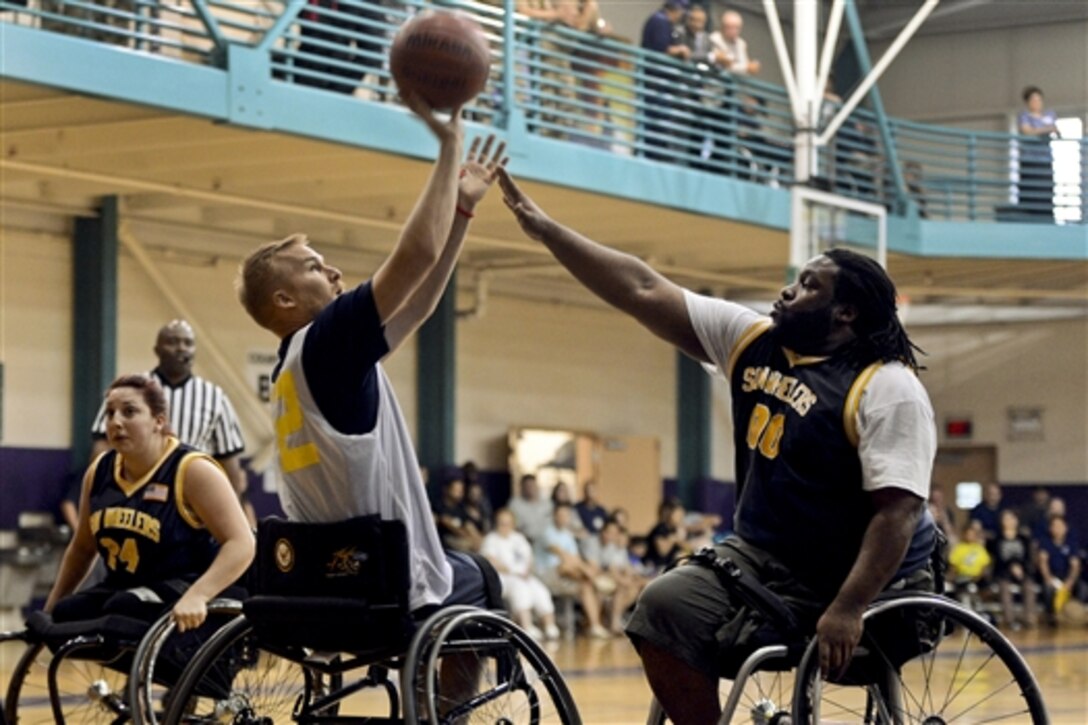 Retired Navy Petty Officer 3rd Class Brian Canich shoots a basketball over Carlos Spence, a member of a local adaptive sports basketball team, at an exhibition game during the 2014 Wounded Warrior Team Navy Trials in Norfolk, Va., June 4, 2014. About 70 seriously wounded, ill and injured sailors and Coast Guardsmen from across the country are competing for a place on Team Navy 2014. 