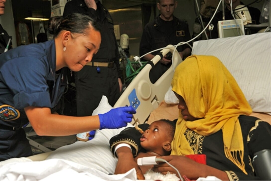 U.S. Navy Petty Officer 2nd Class Katherine Stafford treats a mother and child after a medical evacuation aboard the USS Bataan in the Mediterranean Sea, June 7, 2014. The Bataan and the USS Elrod rendered assistance by providing food, water, medical attention and temporary shelter to 282 persons after receiving a report that an Italian military marine patrol aircraft sighted six small vessels, one of which was sinking. 