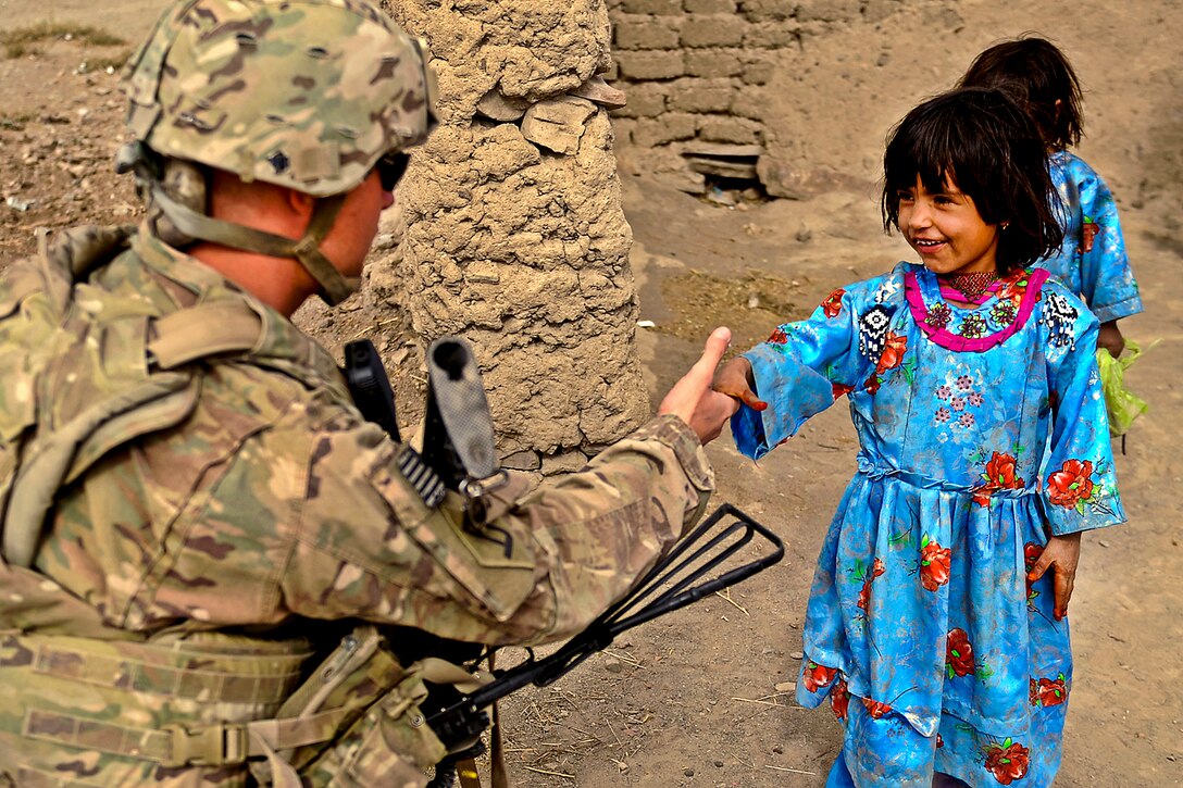 U.S. Army Pfc. Richard Mills greets an Afghan girl in Shinkai, Afghanistan, Nov. 7, 2011. Mills is a rifleman assigned to Provincial Reconstruction Team Zabul and is deployed from the 182nd Infantry Division's, Company C, Massachusetts National Guard.  
