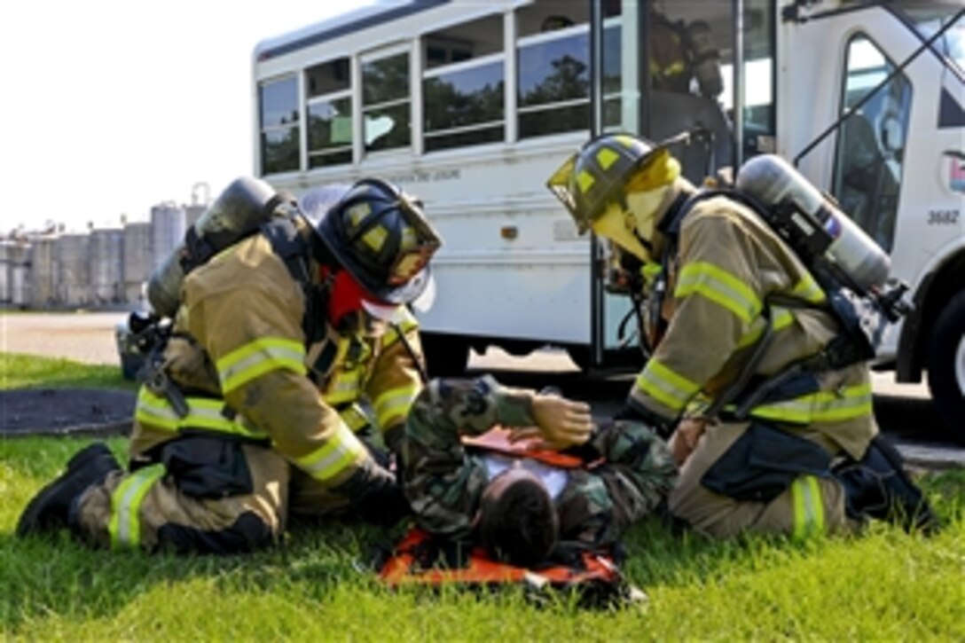 Georgetown county fire and emergency medical service members secure a simulated victim onto a stretcher during a bus crash scenario at a local corporation near Georgetown County Airport, S.C., June 5, 2014. The Guardsmen are working with the state's emergency management division and local emergency agencies to effectively respond to hurricanes and chemical accidents that may threaten the state.  
