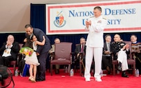 A little girl surprises her father with flowers after he received his National Defense University diploma at the 2014 graduation ceremony, on Fort Lesley J. McNair, Washington, D.C., June 12, 2014. NDU is dedicated to being the premier national security institution focused on advanced joint education, leader development and scholarship.