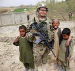 Army Sgt. 1st Class Crystal Dunn, a member of Kentucky's Agribusiness Development Team 4, takes a moment to pose with local children in Afghanistan's Arghandab District on March 24, 2012. Dunn works as a project manager for the area's agricultural and business development programs, which seek to help local Afghan officials train their fellow Afghans on sustainable improvements.