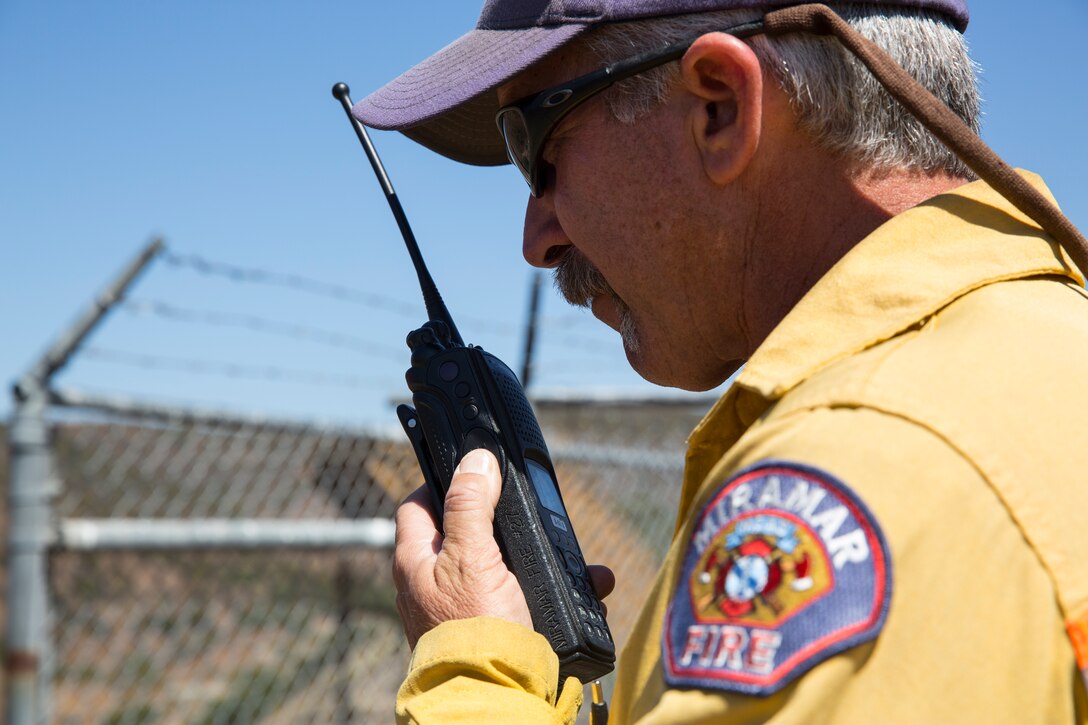 Paul Tompkins, operations chief with the Miramar Fire Department and range incident commander for this prescribed burn, talks on a radio during a prescribed burn aboard Marine Corps Air Station Miramar, Calif., June 12. The Miramar Fire Department worked with the Laguna Hotshots, a crew with the United States Department of Agriculture Forest Service, during the burn. 
