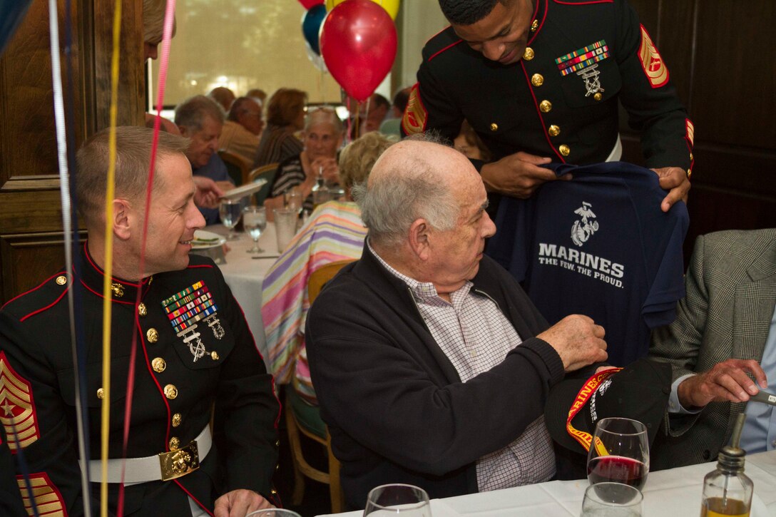 U.S. Marine Corps Gunnery Sgt. Abraham Thompson, a native of Jamaica and a recruiter with Recruiting Station Baltimore, presents Melvin Kabik, a World War II veteran, with a Marine Corps shirt during his 90th birthday party in Baltimore, Md., June 1, 2014. Kabik, a native of Baltimore, enlisted in the Marine Corps when he was 18 years old and became a radio operator in 3rd Battalion, 4th Marine Regiment, and fought in the battles of the Marianas and Okinawa.  (US Marine Corps photo by Sgt Bryan Nygaard/Released)
