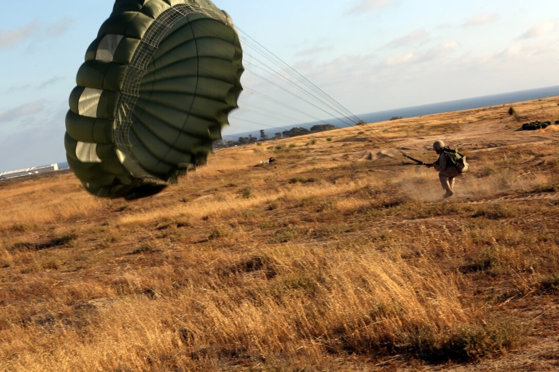 Lance Cpl. Joshua R. Robinson, 24, from Whittier, Calif., with 1st Air Delivery platoon lands after completing a static line jump out of a CH-46 Sea Knight aboard Camp Pendleton, Calif., June 5, 2014. The Marines conducted two day jumps and two night jumps at around 1,500 feet.  Three Marines jumped with full combat gear in order to complete the requirements for their gold wings.