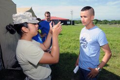 U. S. Army Pfc. Anisa Hernandez, MEDEL human resource specialist, takes a photo of a hurricane victim after she entered his information into the Global MedAid program.  In preparation for the 2014 hurricane season, the Joint Task Force-Bravo Medical Element (MEDEL) conducted a humanitarian assistance/disaster response (HA/DR) exercise at Soto Cano Air Base, Honduras June 12, 2014.  The MEDEL's mission was to establish a forward medical treatment operation capable of providing triage, primary care, surgical capabilities, patient holding and evacuation.  As part of this exercise, a suite of mobile technology applications that run on smartphones and tablets were used to enhance the capabilities of the unit: Global MedAid, Medical Application of Speech Translation (MAST) and GeoSHAPE.  (Photo by U. S. Air National Guard Capt. Steven Stubbs)