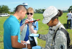 Cynthia Barrigan (left), Telemedicine & Advanced Technology Research Center (TATRC) portfolio manager, communicates with a Spanish-speaking hurricane victim using the Medical Application of Speech Translation (MAST) while U. S. Army 1st Lt. Jewell Hemmings, MEDEL community health nurse, scans the patient's armband with the Global MedAid program.  In preparation for the 2014 hurricane season, the Joint Task Force-Bravo Medical Element (MEDEL) conducted a humanitarian assistance/disaster response (HA/DR) exercise at Soto Cano Air Base, Honduras June 12, 2014.  The MEDEL's mission was to establish a forward medical treatment operation capable of providing triage, primary care, surgical capabilities, patient holding and evacuation.  As part of this exercise, a suite of mobile technology applications that run on smartphones and tablets were used to enhance the capabilities of the unit: Global MedAid, Medical Application of Speech Translation (MAST) and GeoSHAPE.  (Photo by U. S. Air National Guard Capt. Steven Stubbs)