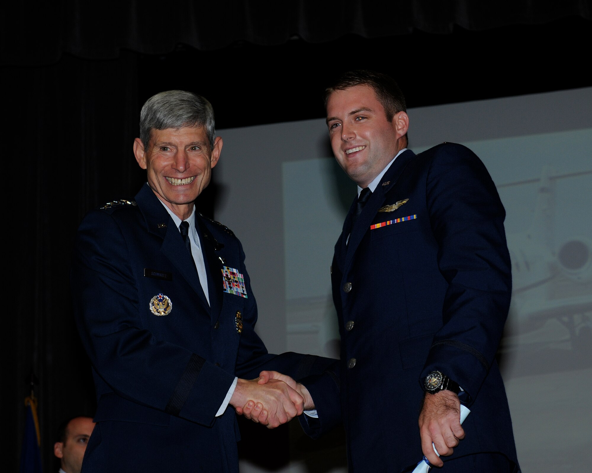 Gen. (Ret.) Norton Schwartz, Former Chief of Staff of the Air Force, shakes the hand of his godson, 2nd Lt. Patrick Wheble, SUPT Class 14-10 graduate, at the graduation ceremony for SUPT Class 14-10 June 13 at Kaye Auditorium. 
