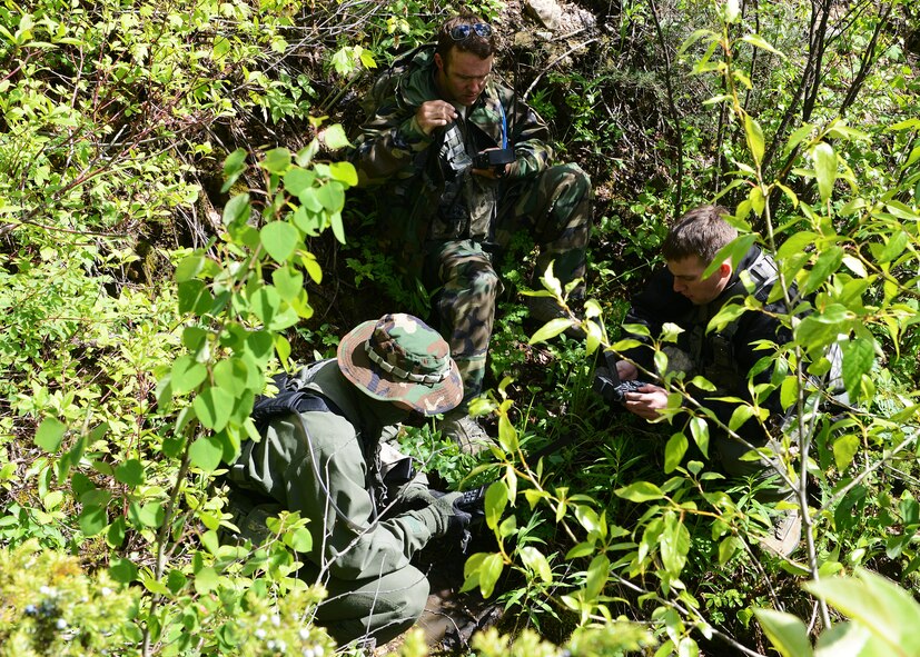 (Clockwise, left to right) 40th Helicopter Squadron UH-1N Huey pilots, Capts. Tyler Williams, Joshua Hallford and Zachary Minner, hide in a ravine during a Survival, Evasion, Resistance and Escape field training exercise at Lewis and Clark National Forest on June 11 in Monarch, Mont. Three Nuclear Advanced Designated Marksmen Airmen from the 341st Security Forces Group Tactical Response Force participated in the eight-hour FTX. (U.S. Air Force photo/Senior Airman Katrina Heikkinen)