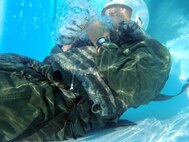 Lt. Col. Thomas Higgins, 40th Helicopter Squadron director of staff, experiences water going up his nose as he breathes into a C-bottle during water survival skills training at the Malmstrom Air Force Base pool on June 10. Members of the 40th HS endured survival, evasion, resistance and escape training June 9 to 13. (U.S. Air Force photo/Senior Airman Katrina Heikkinen)