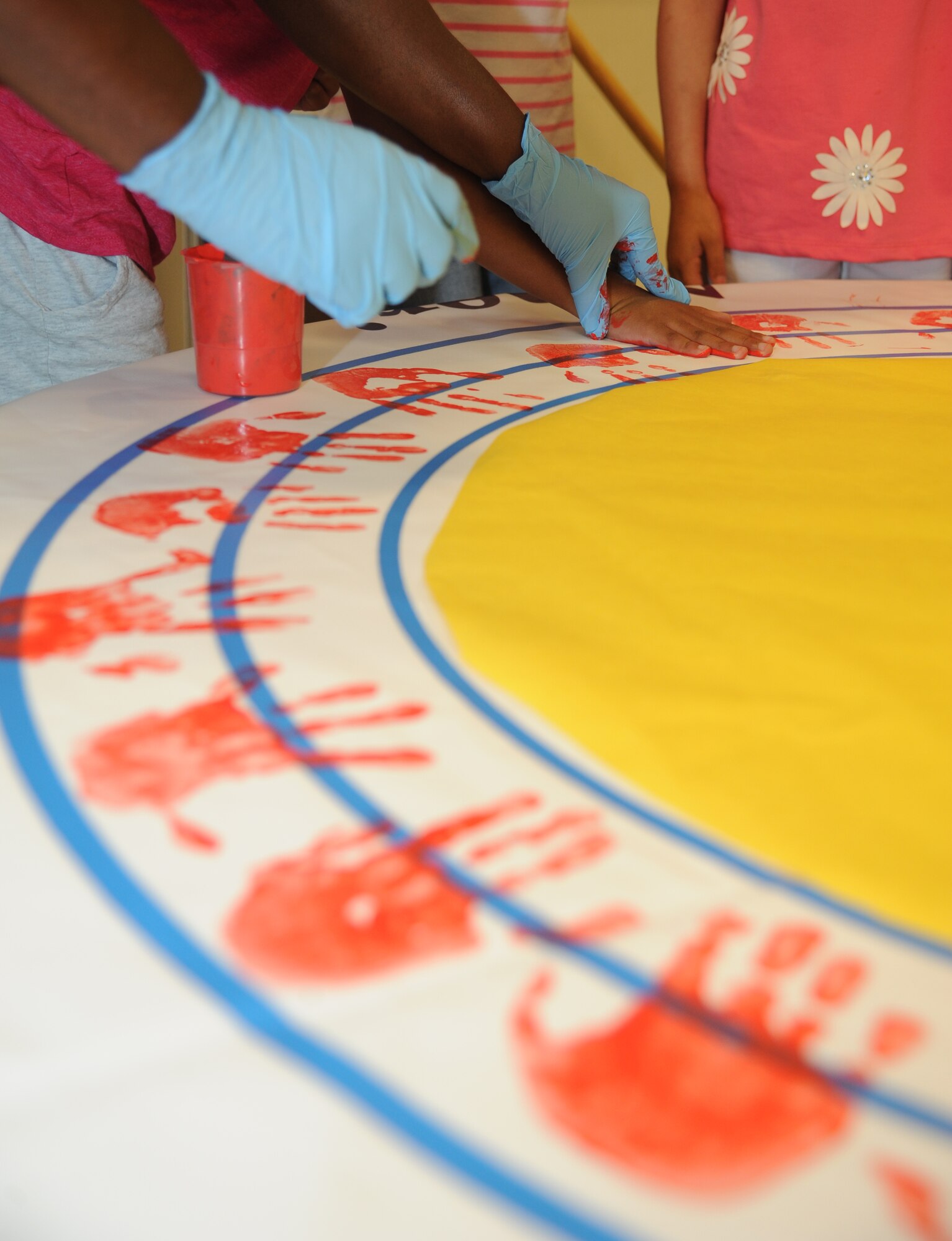 Children at the Keesler Youth Center decorate a banner with their handprints June 13, 2014, at the Youth Center, Keesler Air Force Base, Miss.  The banner will be presented to the Armed Forces Retirement Home on behalf of the Ringling Brothers Circus.  (U.S. Air Force photo by Kemberly Groue)