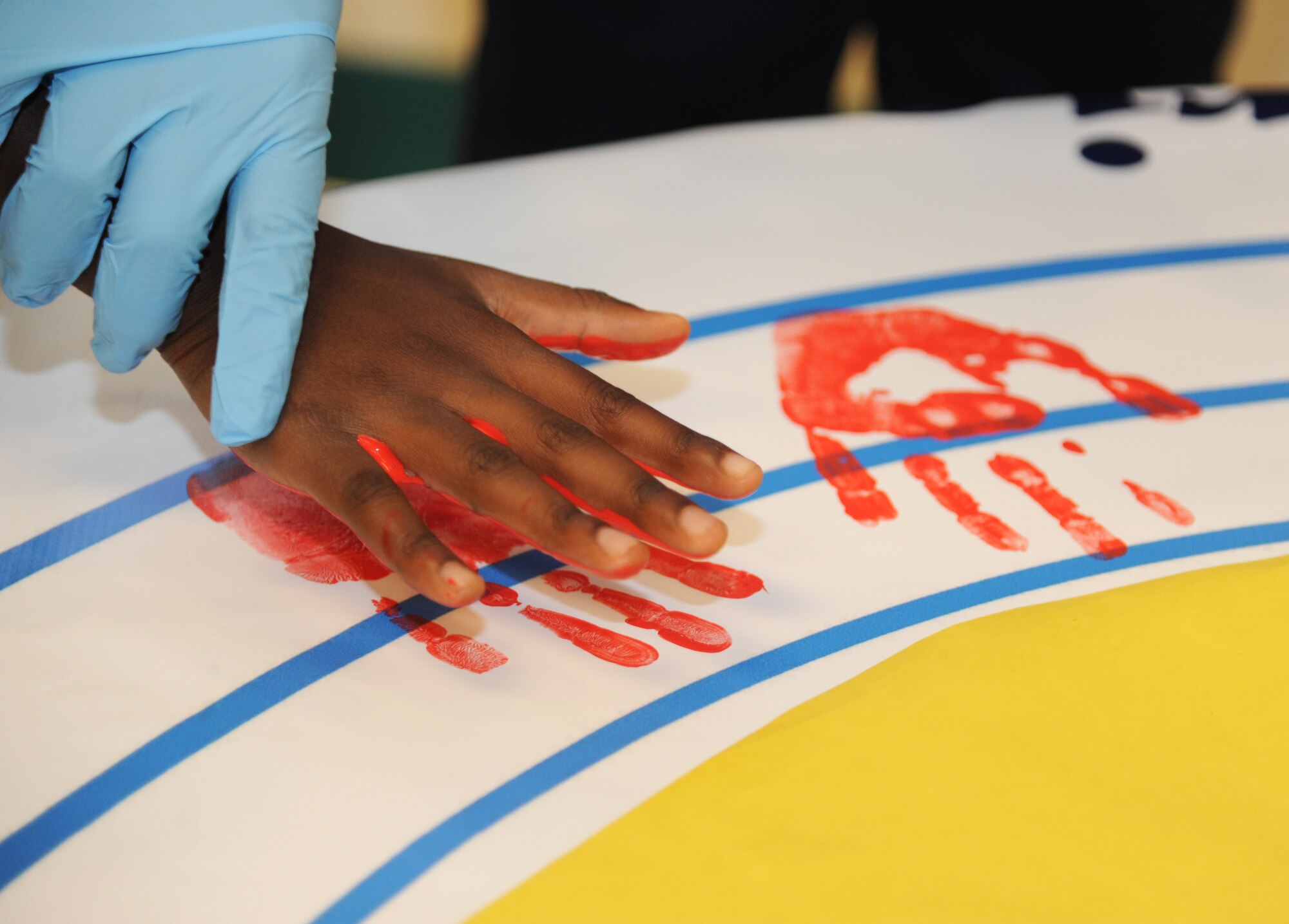 Children at the Keesler Youth Center decorate a banner with their handprints June 13, 2014, at the Youth Center, Keesler Air Force Base, Miss.  The banner will be presented to the Armed Forces Retirement Home on behalf of the Ringling Brothers Circus.  (U.S. Air Force photo by Kemberly Groue)