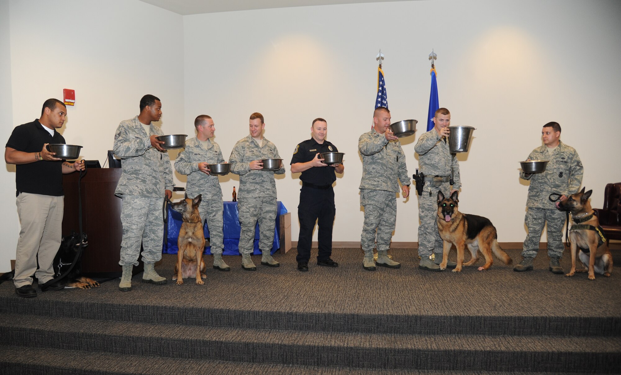 Members of the 81st Security Forces Squadron conduct a ceremonial toast with dog bowls in honor of military working dog, Gino, during his retirement ceremony June 12, 2014, at the Roberts Consolidated Maintenance Facility, Keesler Air Force Base, Miss.  Gino is eleven years old and served nine years of military service to the Air Force and has been adopted by his handler, Staff Sgt. Javonnia Peak, 81st SFS. (U.S. Air Force photo by Kemberly Groue)