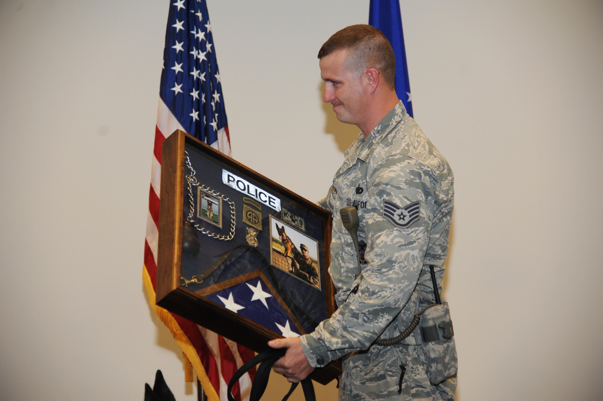 Staff Sgt. Javonnia Peak, 81st Security Forces Squadron dog handler, holds a shadow box that was presented to him and his military working dog, Gino, during the retirement ceremony  of Gino June 12, 2014, at the Roberts Consolidated Maintenance Facility, Keesler Air Force Base, Miss.  Gino is eleven years old and served nine years of military service to the Air Force and has been adopted by his handler, Peak. (U.S. Air Force photo by Kemberly Groue)
