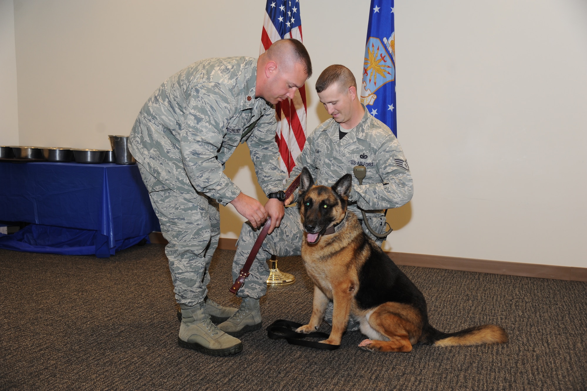 Maj. Brian Fitzpatrick, 81st Security Forces commander, helps Staff Sgt. Javonnia Peak, 81st SFS dog handler, change the collar of military working dog, Gino, during Gino’s retirement ceremony June 12, 2014, at the Roberts Consolidated Maintenance Facility, Keesler Air Force Base, Miss.  Gino is eleven years old and served nine years of military service to the Air Force and has been adopted by his handler, Peak. (U.S. Air Force photo by Kemberly Groue)