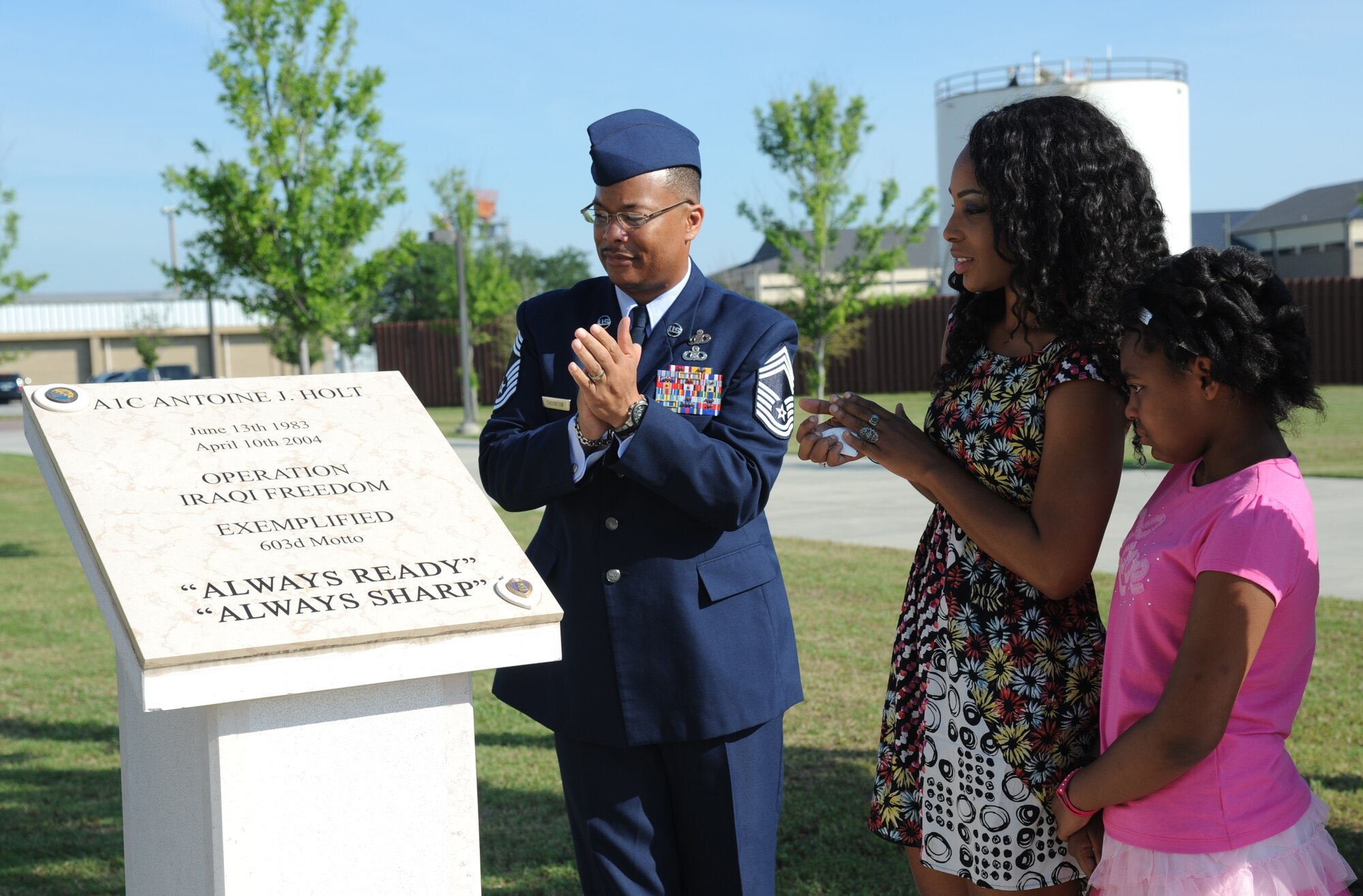 Chief Master Sgt. Roger Thornton, 607th Air Operations Center, Osan Air Base, Republic of Korea; the wife and daughter of the late Airman 1st Class Antoine Holt, Patricia and Carmen, admire a memorial honoring Holt during a re-dedication ceremony June 12, 2014, in front of Avery Manor at Keesler Air Force Base, Miss.  Holt, a former student in the 334th TRS, lost his life April 10, 2004 while at Balad Air Base, Iraq, when his tent was hit by a mortar attack.  (U.S. Air Force photo by Kemberly Groue)