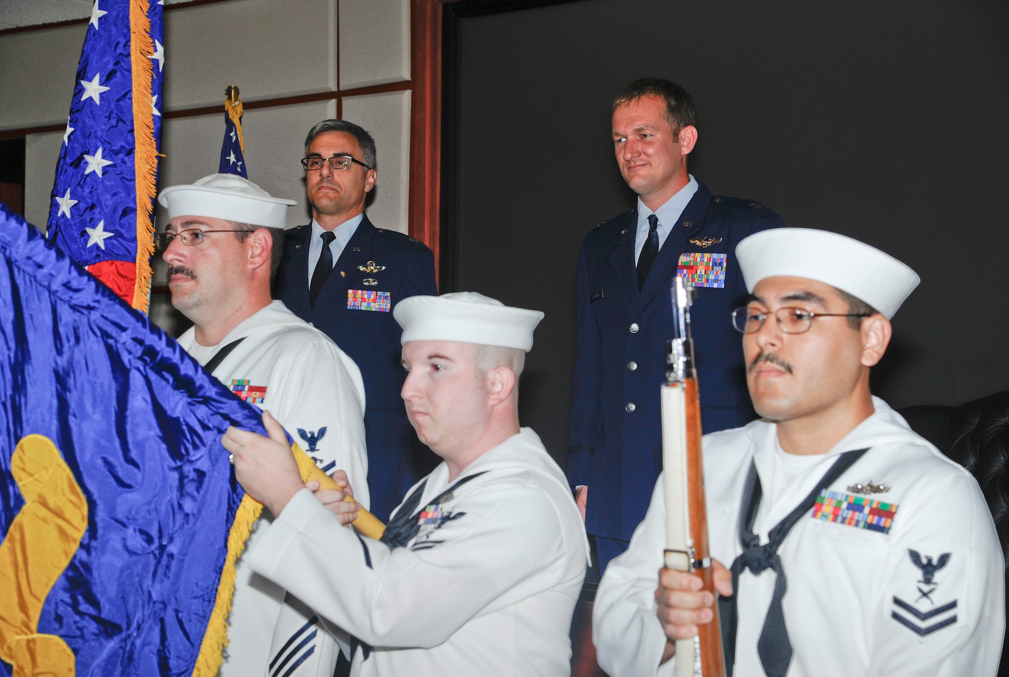 Retired Lt. Col. Jim Wurzer and Capt. Jason Scoggins, 22nd Air Refueling Squadron navigator, stand at attention as U.S. Navy Honor Guard from the Navy Operational Support Center present colors at a retirement ceremony June 12, 2014, at McConnell Air Force Base, Kan. They honored Air Force Capt. Jason Scoggins, 22nd Air Refueling Squadron navigator, who retired after more than 17 years of service. Scoggins served his first nine years as an enlisted sailor. (U.S. Air Force photo/Airman 1st Class John Linzmeier)