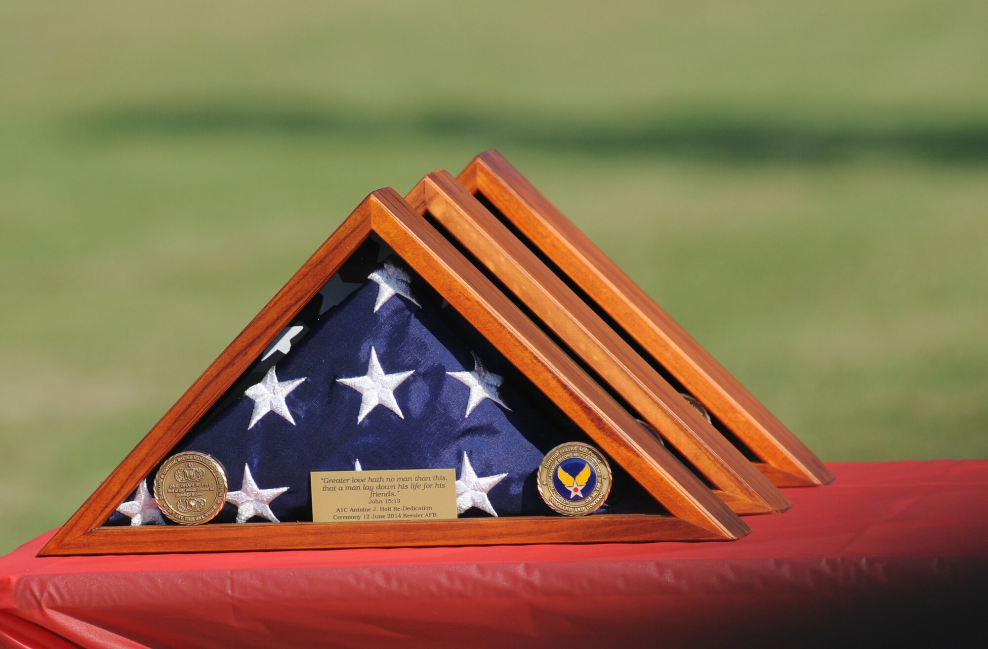 Shadow boxes containing U.S. American Flags sit on display for the late Airman 1st Class Antoine Holt during a re-dedication ceremony to honor Holt with a memorial June 12, 2014, in front of Avery Manor at Keesler Air Force Base, Miss.  Holt, a former student in the 334th Training Squadron, lost his life April 10, 2004 while at Balad Air Base, Iraq, when his tent was hit by a mortar attack.  (U.S. Air Force photo by Kemberly Groue)