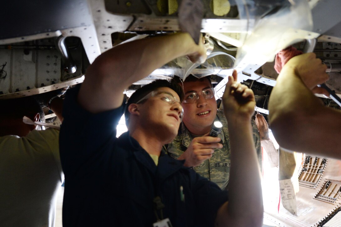 Senior Airman Josh Gomez, 28th Maintenance Squadron crew chief (left), explains how to reinstall a hydraulic line clamp to Cadet 2nd Class Kevin Mitchell, U.S. Air Force Academy cadet, during a cadet group visit of Ellsworth Air Force Base, S.D., June 9, 2014. Prior to being commissioned as officers upon graduation, USAFA cadets visit different installations to gain a better understanding of missions being accomplished at Air Force bases. (U.S. Air Force photo by Airman 1st Class Rebecca Imwalle/Released)