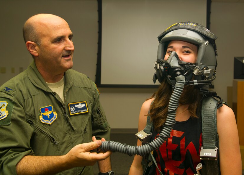 Colonel Rodney Petithomme, 54th Fighter Group commander, helps Kelsie Malone, a Showtime Studio dance member, put on flight helmet during a tour at Holloman Air Force Base, N.M., June 9. Members from Showtime Studio, a hip-hop studio located at the Boys and Girls Club in Alamogordo, N.M., visited the 54th Fighter Group. The members got a hands on look at the squadron flight equipment and F-16 Fighting Falcon. (U.S. Air Force photo by Airman 1st Class Leah Ferrante/Released) 
