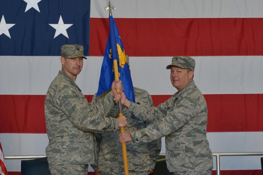 U.S. Air Force Col. Bryan Harris, 20th Maintenance Group commander, receives the 20th MXG guidon from Col. Stephen Jost, 20th Fighter Wing commander, as he assumes command, Shaw Air Force Base, S.C. June 13, 2014. Col. Helen Brasher relinquished command to Harris after being the commander of the 20th MXG for three years. (U.S. Air Force photo by Senior Airman Ashley L. Gardner/ Released)
