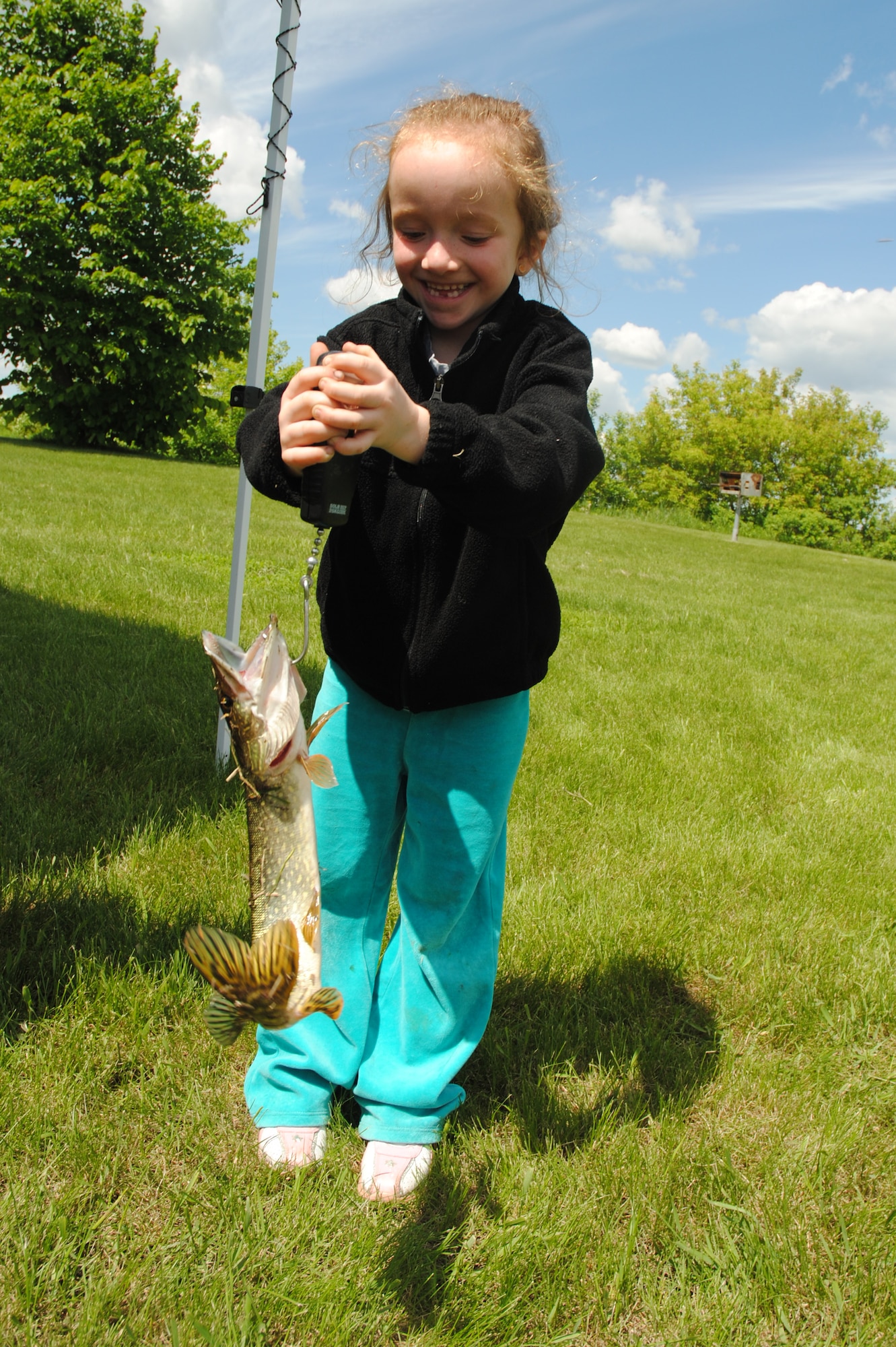 Gracie Kuglin, weighs a feisty 14-ounce northern pike, which she caught on June 7, 2014, during the 26th Annual Kids’ Fishing Derby at Larimore Dam, N.D. The 6-year-old, from Grand Forks was one of more than 160 children to register for the competition. Children from communities such as Park River, Larimore, Arvilla and Grafton among others participated in the family friendly event. (U.S. Air Force photo/Staff Sgt. Luis Loza Gutierrez)
