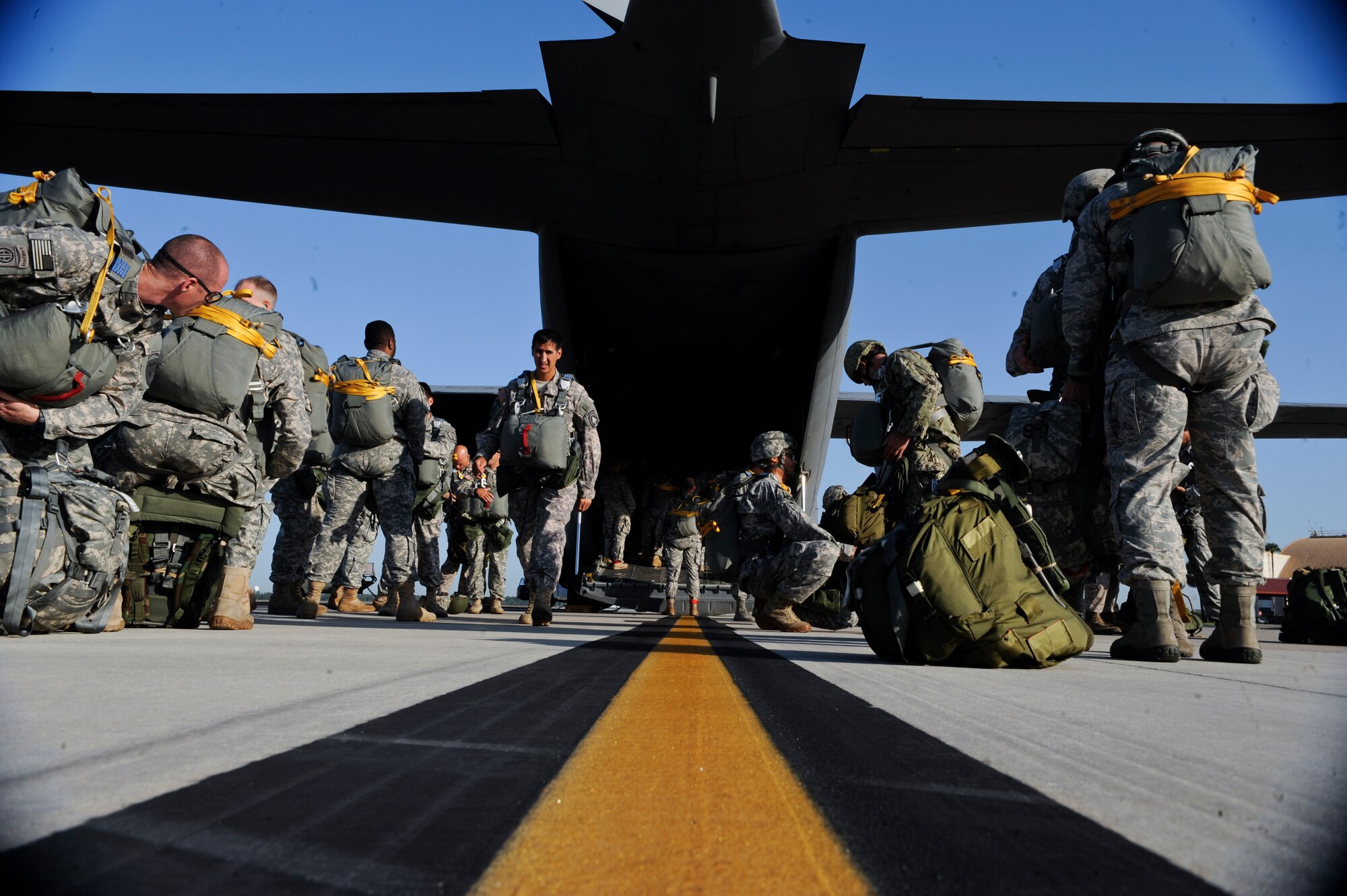 Maj. Jon Narvaes, Special Operations Command branch chief, walks to gather his gear as other joint service personnel prepare to board May 21, 2014 at MacDill Air Force Base, Fla. This type of joint assignment is Tech. Sgt. Veronica Gatta’s, Joint Communications Support Element Direct Communications Support team chief, first in her career and has provided an extremely rare and motivating experience. (U.S. Air Force photo by Senior Airman Vernon L. Fowler Jr. /Released)
