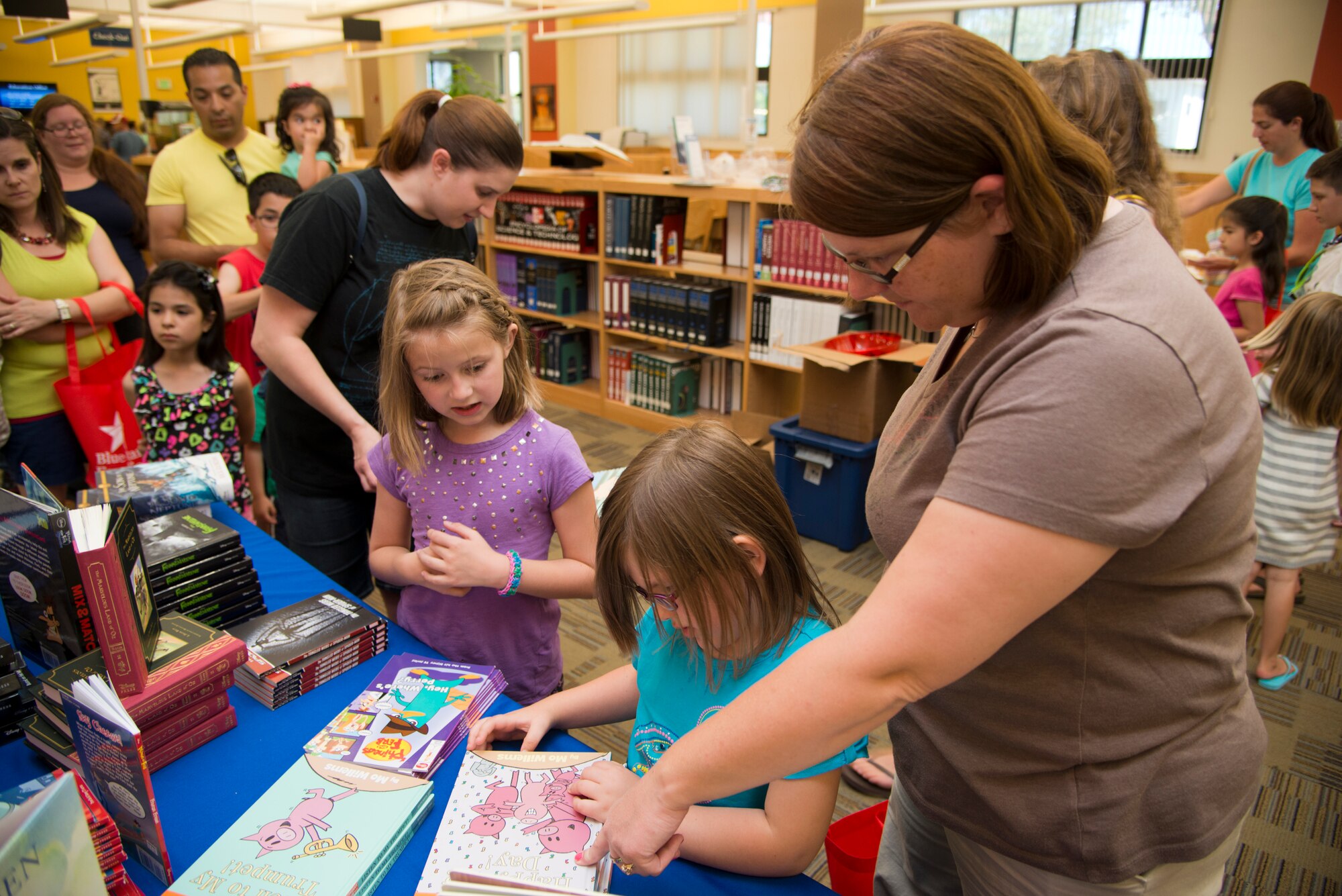 Jenny Felsen, Blue Star Families Travis chapter director, helps children decide what book to pick out at the Mitchell Memorial Library during Books on Bases event June 4. Approximately 250 children attended the event where they got a free book, crafts and snacks. (U.S. Air Force photo/Senior Airman Nicole Leidholm)