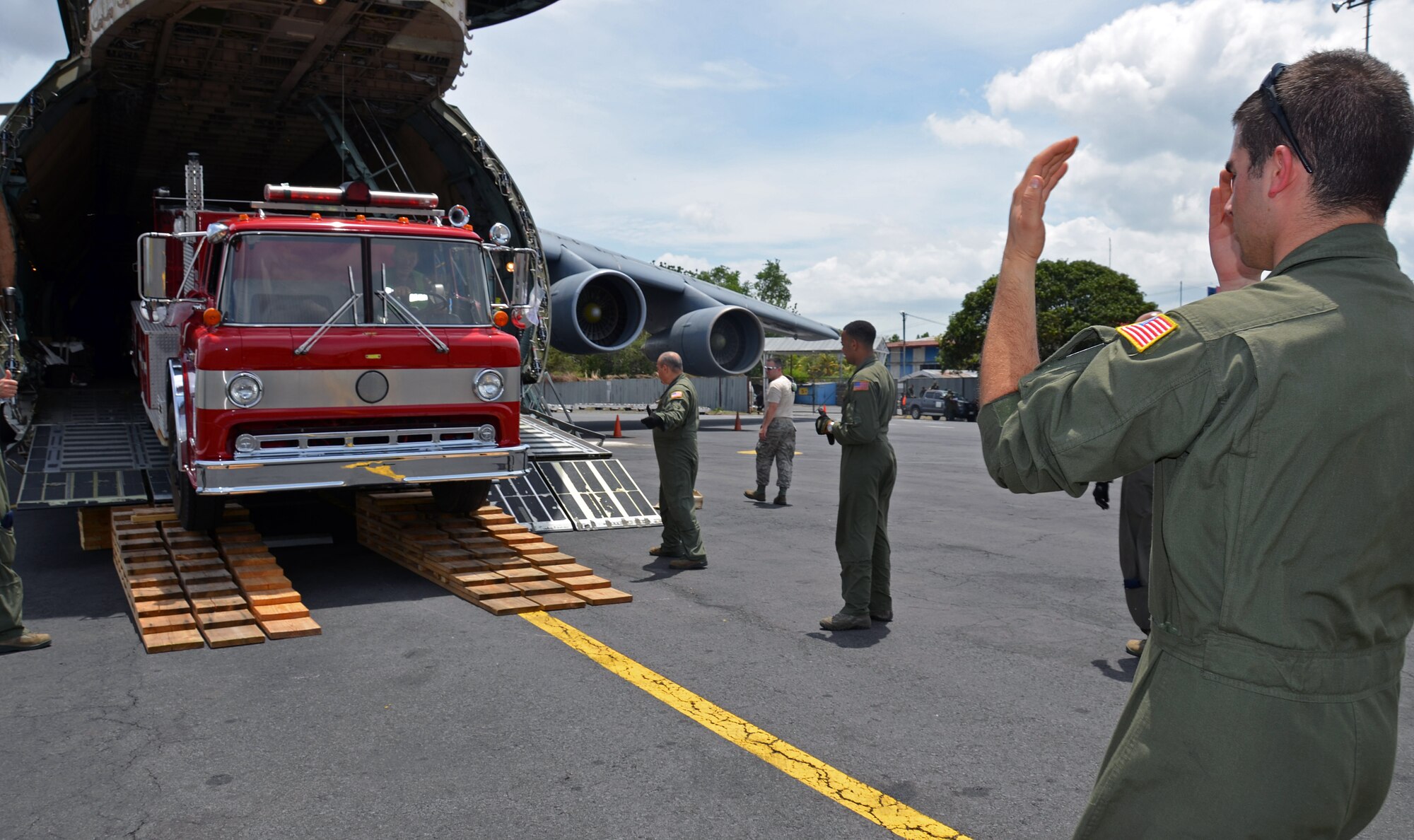 SrA. Michael Niccoll, 337th Airlift Squadron Loadmaster, marshals a fire truck off the Westover C-5, June 10, 2014 in Managua Nicaragua. This Denton Amendment mission delivered an ambulance and two fire truck vehicles to Nicaragua June 10 on behalf of the Wisconsin/Nicaragua Partners of the Americas Incorporated. (U.S. Air Force photo/SSgt. Kelly Goonan)