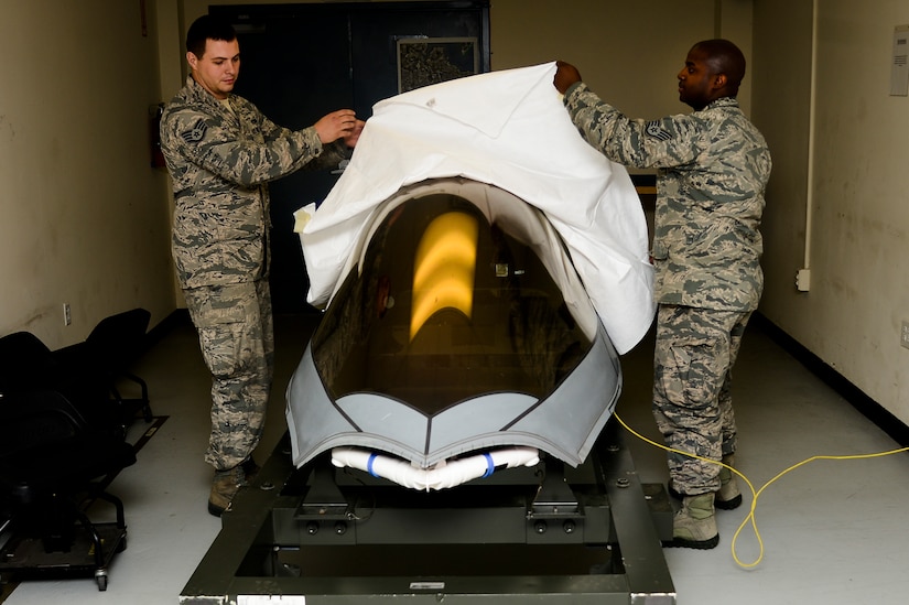 United States Air Force Staff Sgt. William Harth, 1st Maintenance Squadron Aircrew Egress craftsman, left, and Staff Sgt. Angelo Lowe, 1st MXS Aircrew Egress journeyman, remove the cover of an F-22 Raptor canopy at Langley Air Force Base, Va., June 9, 2014. Egress Airmen ensure all components responsible for safely ejecting a pilot from an F-22 Raptor are functioning properly and efficiently. (U.S. Air Force photo by Senior Airman Kayla Newman/Released) 